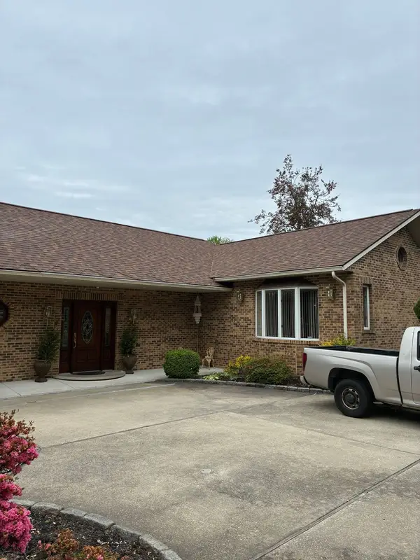 Brick ranch home with a brown asphalt shingle roof and a pickup in the driveway