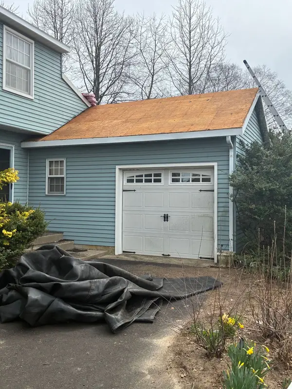Garage roof with fresh decking and tarps on the driveway