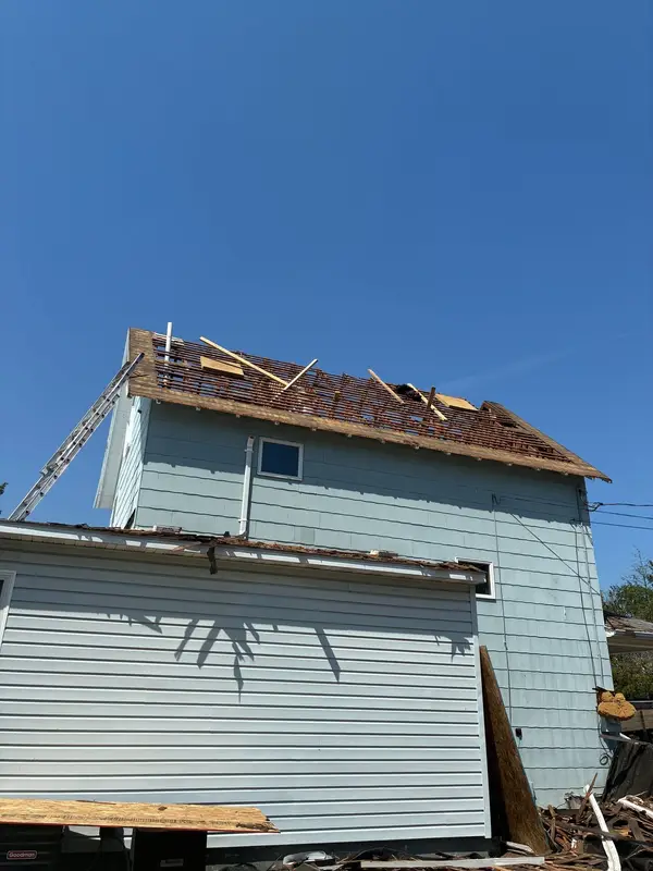 Two-story home with the old roof torn off down to the rafters during replacement