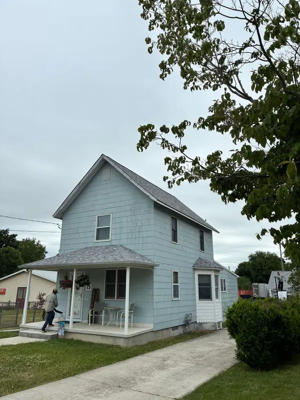 Roofing crew arriving at a two-story light blue home with a front porch